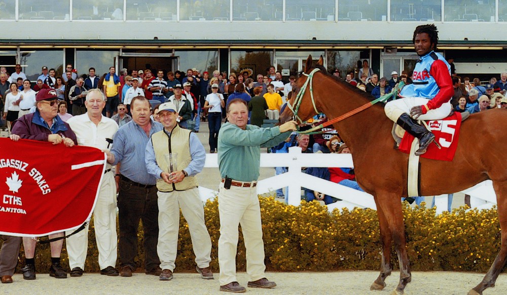 Peter Funk, George Friesen and owner Jake Penner display the banner in the winner’s circle, after jockey Juan Crawford rode Speedy Treat to victory in the Agassiz Stakes race at Assiniboia Downs.