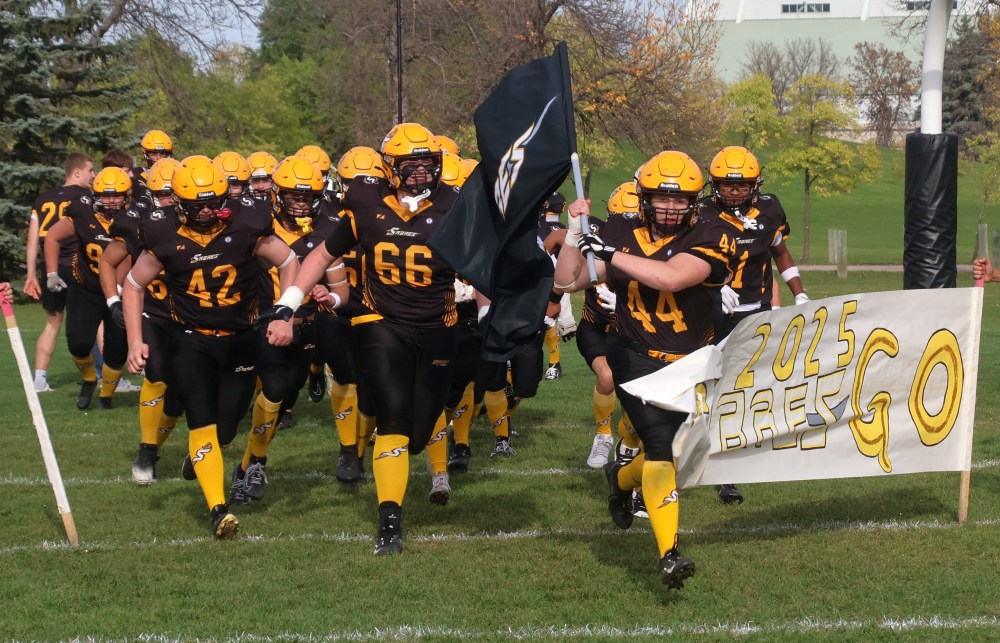 Seth Friesen leads the Varsity Steinbach Regional Sabres football team onto the field before their homecoming game Oct. 3. (Cassidy Dankochik The Carillon)