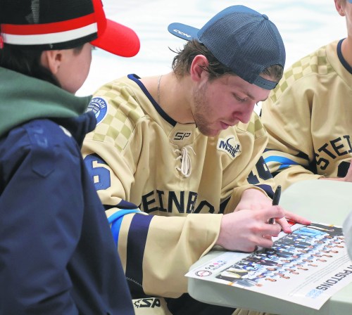 Connor Paronuzzi signs a team poster following the Pistons final regular season game of the season. (Cassidy Dankochik The Carillon)