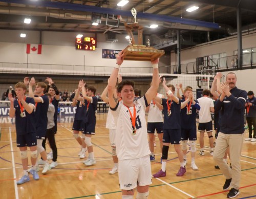 Libero Kade Lepp hoists the Manitoba Colleges Athletic Conference championship trophy to the crowd following Providence's win March 1. (Cassidy Dankochik The Carillon)