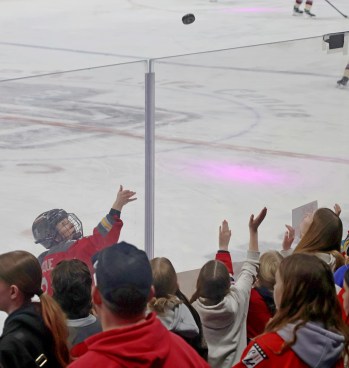 Jocelyne Larocque tosses a puck to some of the hundreds of fans who crowded the boards to watch warm-ups during the PWHL takeover tour game. (Cassidy Dankochik The Carillon)