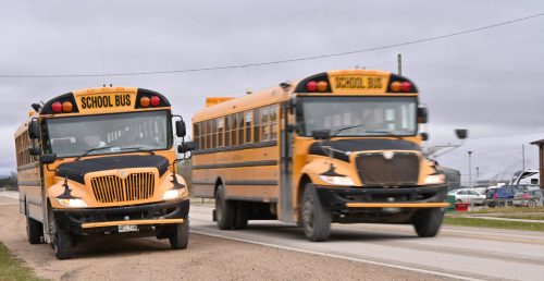 ALEX LAMBERT THE CARILLON A 

A Seine River School Division bus drives past an idling SRSD bus which waits to line up at Dawson Trail School in Lorette.