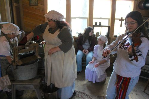 CARILLON ARCHIVES 

Milaine Fillion (left) keeps clothes clean the old-fashioned way as Julie Fillion fiddles during the Sugaring Off Festival in St Pierre. The festival runs from April 11 to 12 and is located at 432 Joubert St.