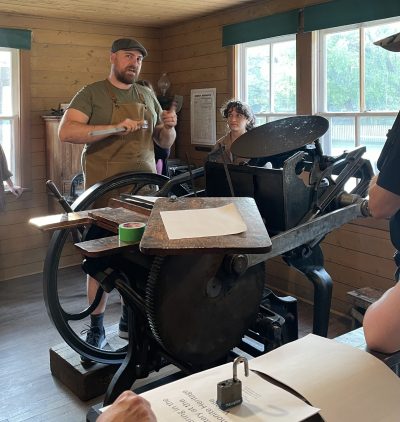 Museum interpreters demonstrate the workings of a printing press.