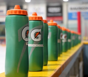 Water bottles line the side of the bench before the start of a hockey game. (Cassidy Dankochik Carillon Archives)
