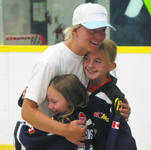 Cassidy Dankochik / The Carillon 

Montreal Victoire defender Kati Tabin shares a hug with Oaklynn Pollins and Lilian Lavoie, who attended the Walter Cup champion’s celebration in Oakbank while wearing their Springfield IceHawks jerseys.