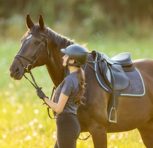 Young woman rider with her horse in evening sunset light. Outdoor photography in lifestyle mood