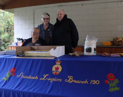 GREG VANDERMEULEN THE CARILLON 

From left, Royal Canadian Legion Branch #190 executive members Juanita Brown, Lauren Bilbey and Keith Duncan stand behind their banner during a celebration at A.D. Penner Park on Sept. 26.